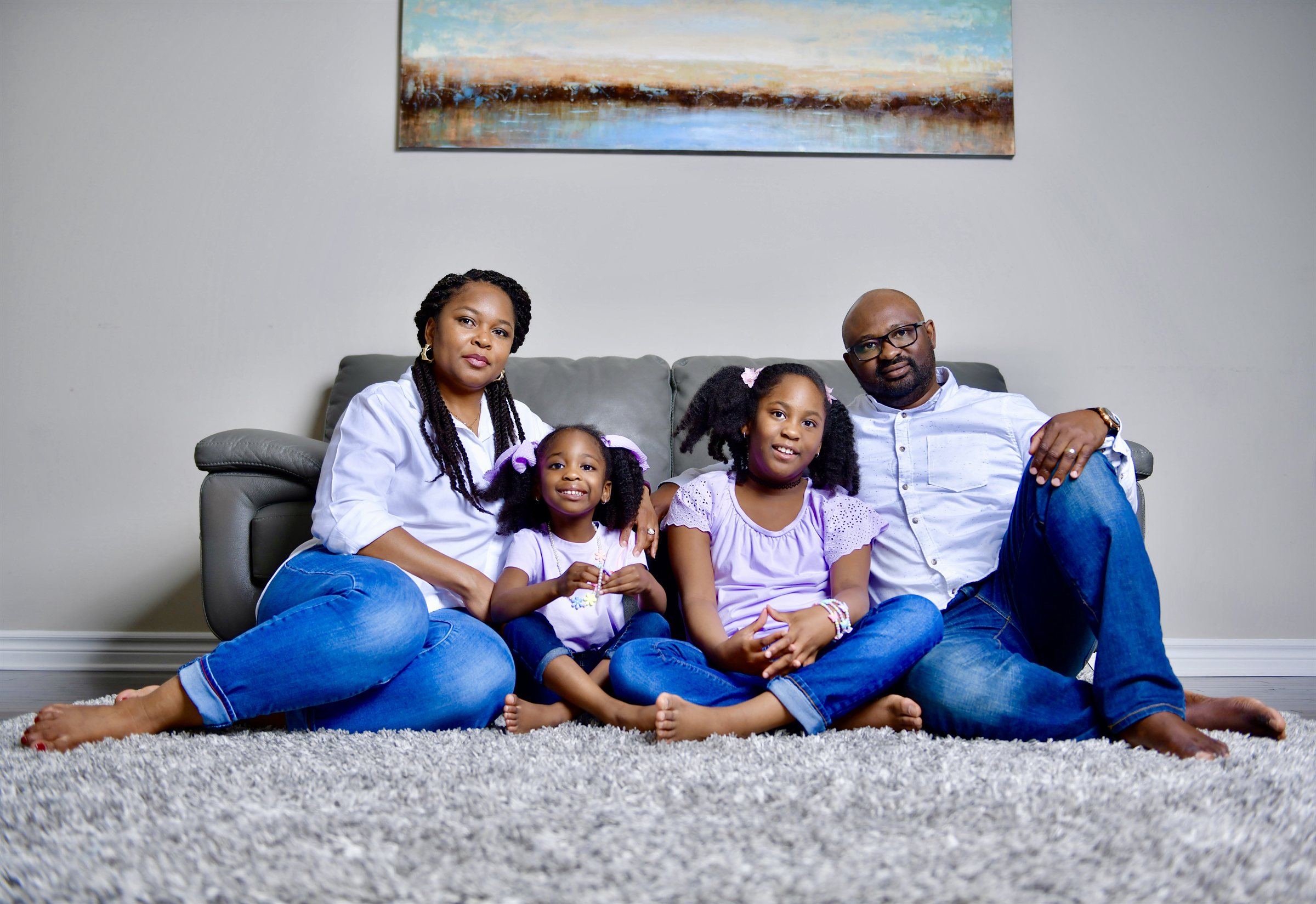 Parents and two daughters sitting together on a rug at home