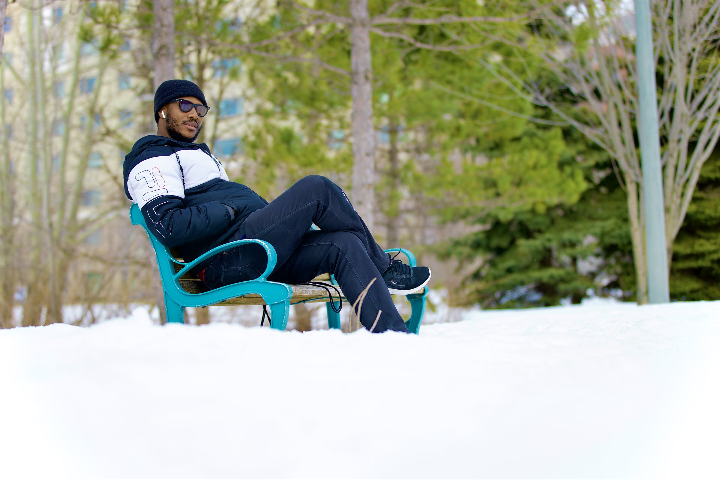 Man relaxing on a teal park bench in fresh snow